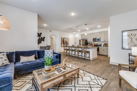 A modern living room with a blue velvet sofa and a coffee table in the center.
